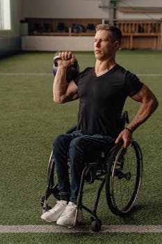 Man in wheelchair performing kettlebell workout indoors, showcasing adaptive fitness.