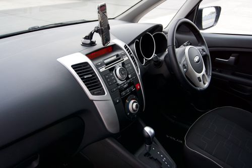 Free Sleek car dashboard with smartphone mount, steering wheel, and controls. Ideal for modern automotive design themes. Stock Photo