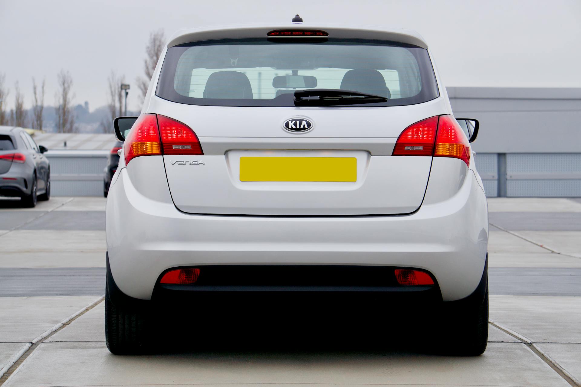 A white Kia Venga hatchback photographed from the rear in an outdoor parking lot.