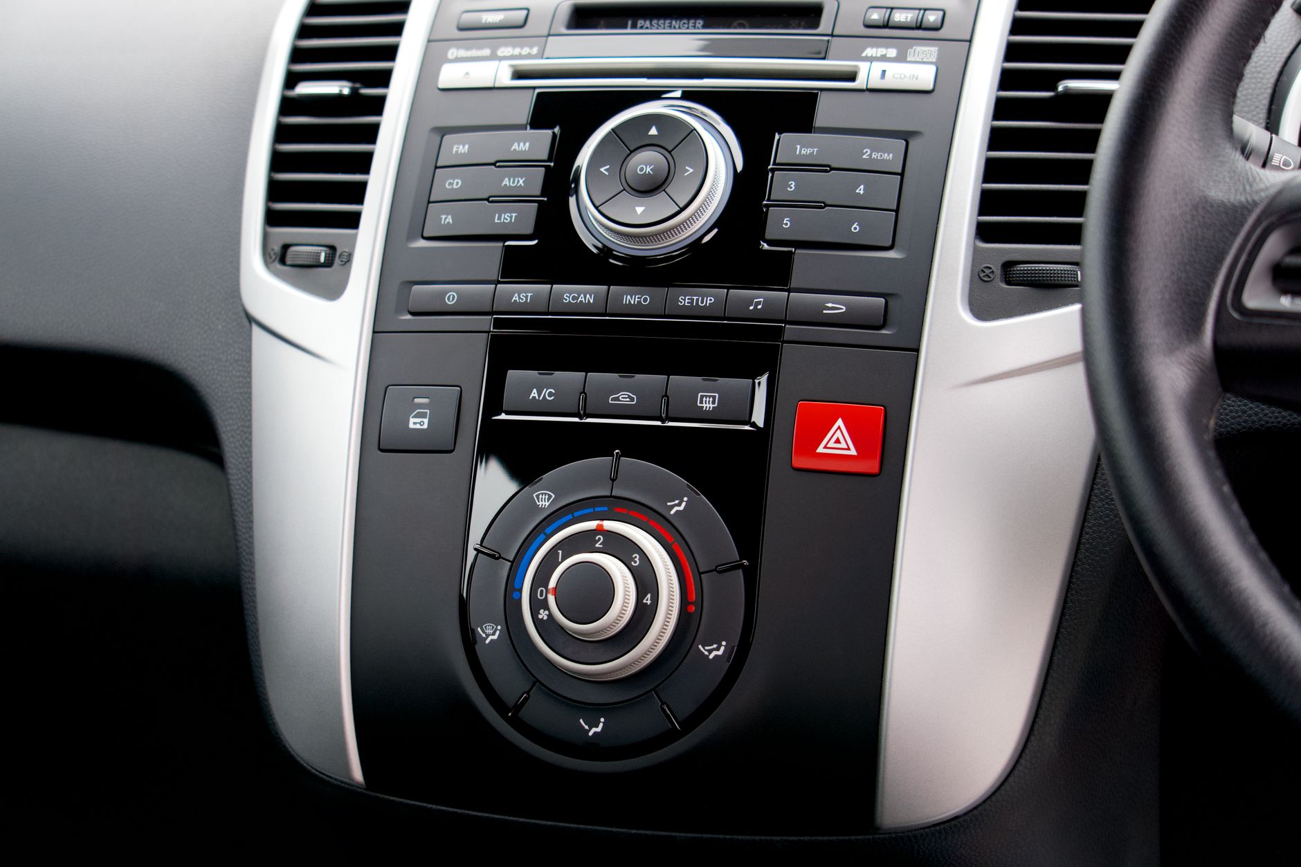 Close-up of a car's dashboard featuring buttons, dials, and a steering wheel.