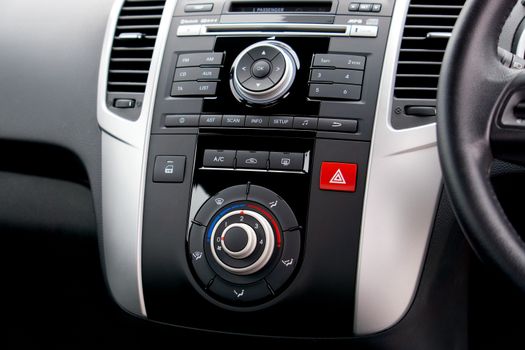Close-up of a car's dashboard featuring buttons, dials, and a steering wheel.