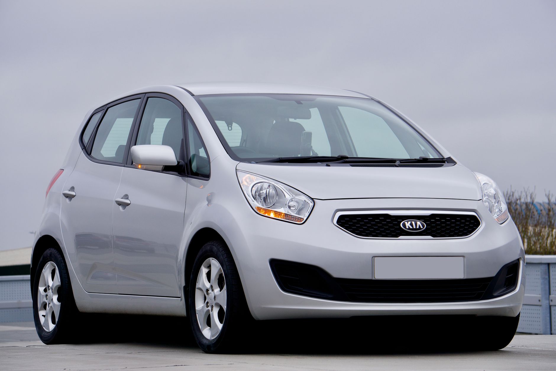 Silver Kia hatchback car parked outdoors in the UK with a clear sky backdrop.