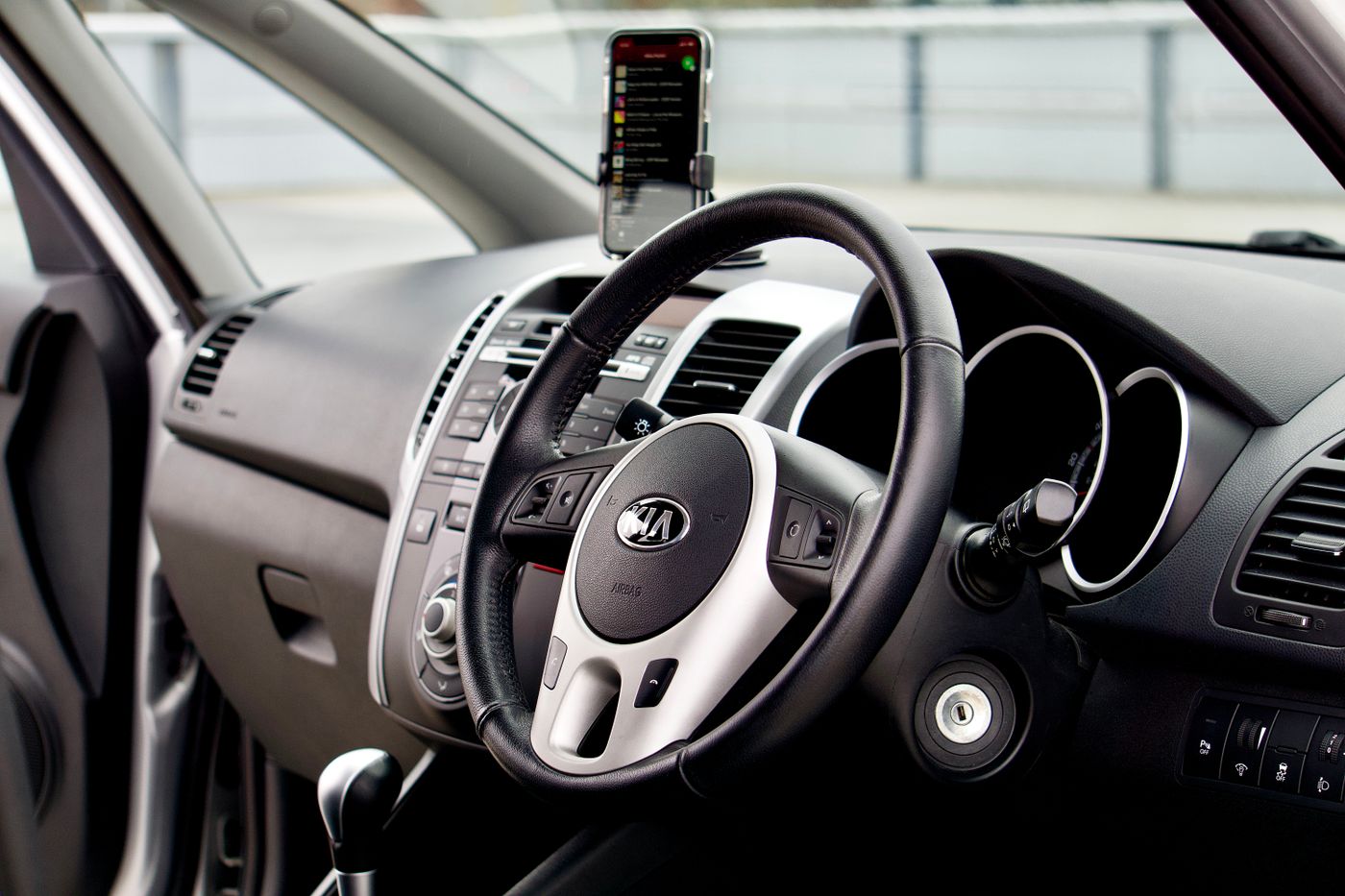 Smartphone mount positioned beside the dashboard and steering wheel inside a car