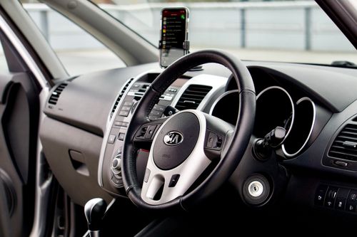Free Close-up of a modern car interior featuring a dashboard, steering wheel, and smartphone mount. Stock Photo