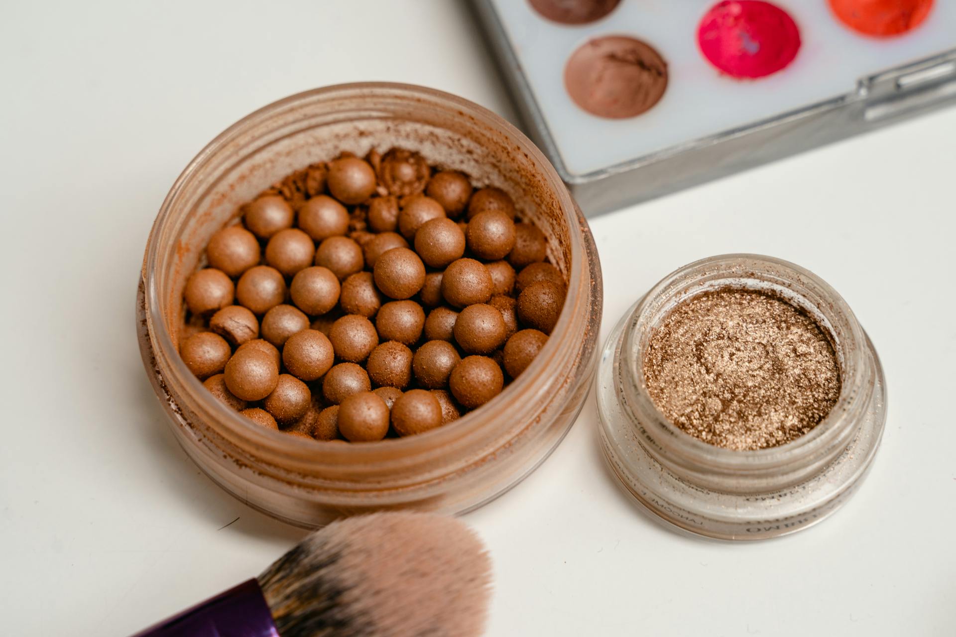 Macro shot of cosmetic powder pearls and brushes with colorful palette.