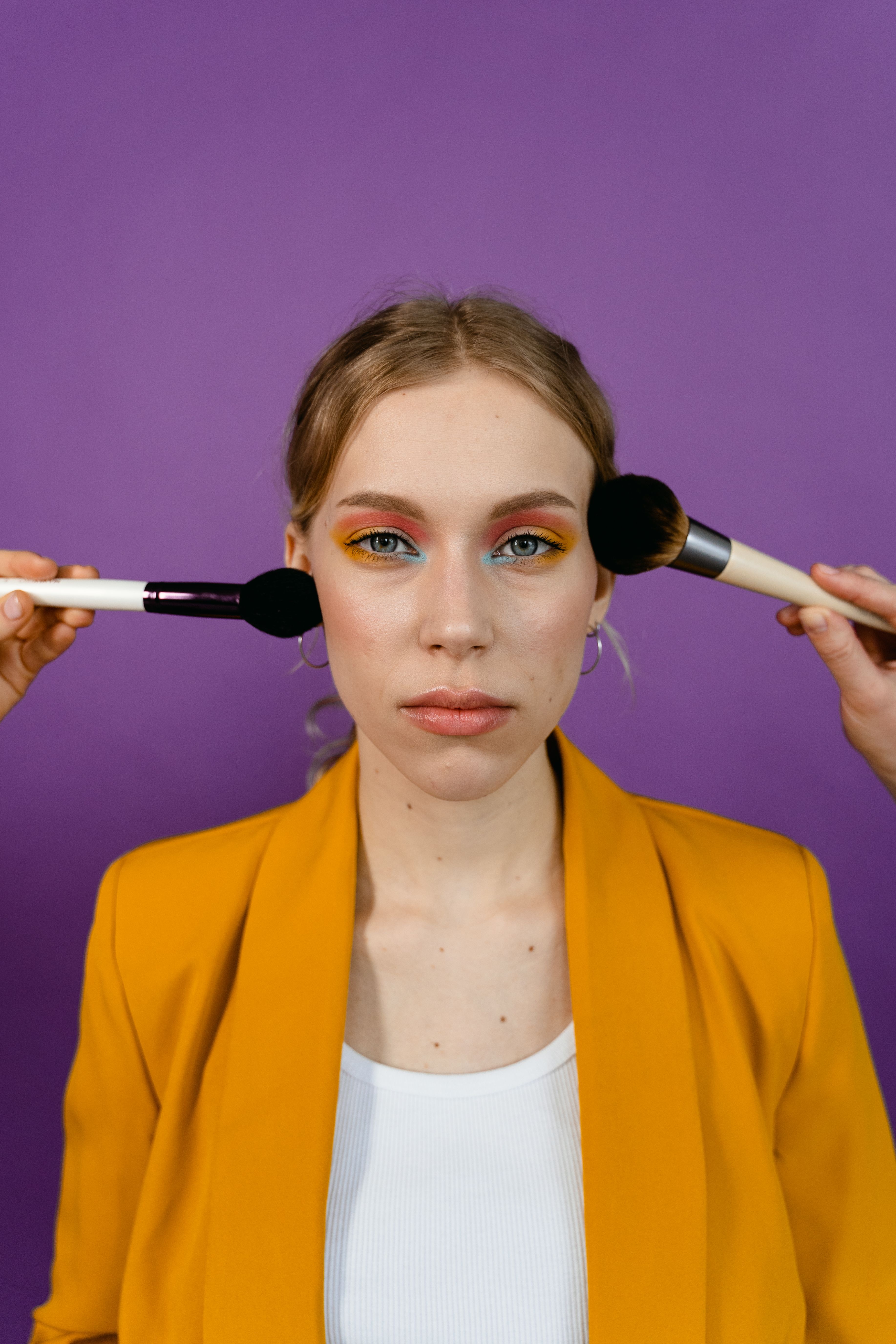 A Person Applying Makeup on a Woman in Yellow Blazer · Free Stock Photo