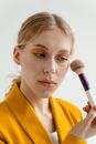 Woman in Yellow Collared Shirt Holding Makeup Brush