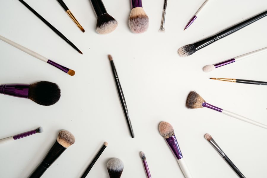 Hand holding Oakmoss makeup brushes against pink