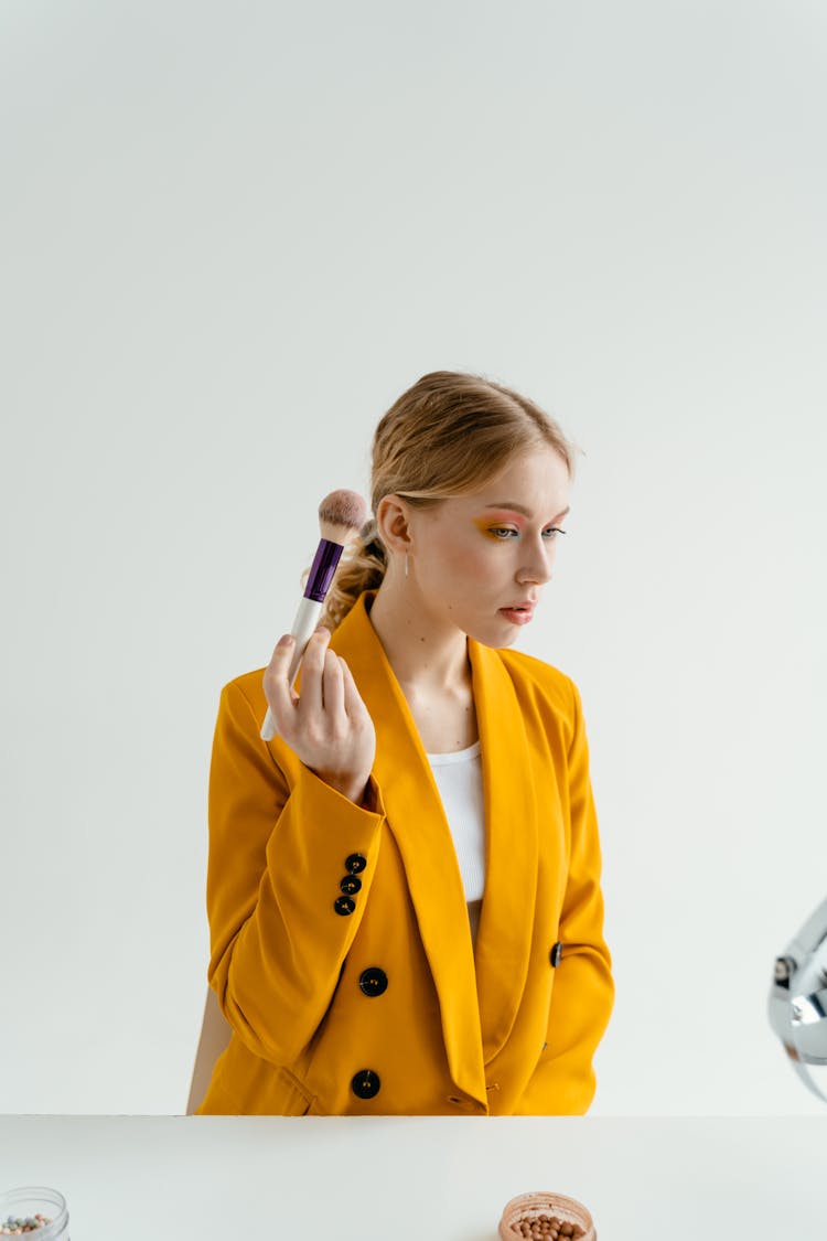 Woman In Yellow Coat Holding Makeup Brush