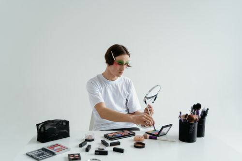Free A person using vibrant eyeshadow and makeup brushes for a creative expression indoors. Stock Photo