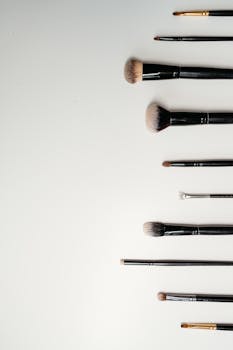 Top view flat lay of makeup brushes on a white background, ideal for beauty themes.
