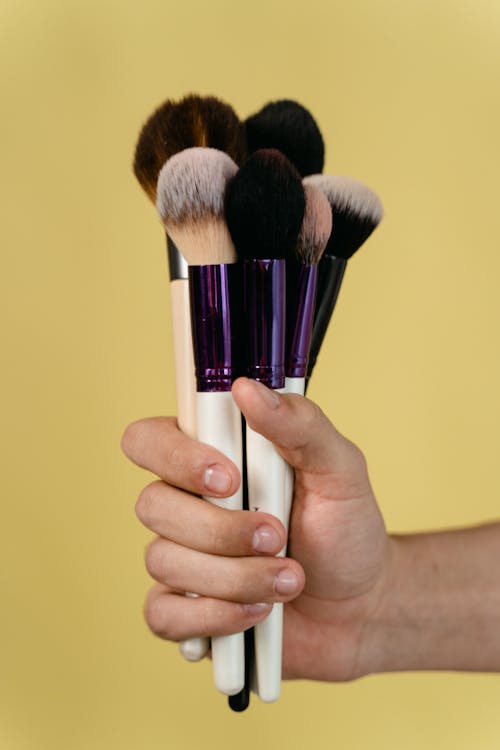 Person Holding Black and Silver Makeup Brush