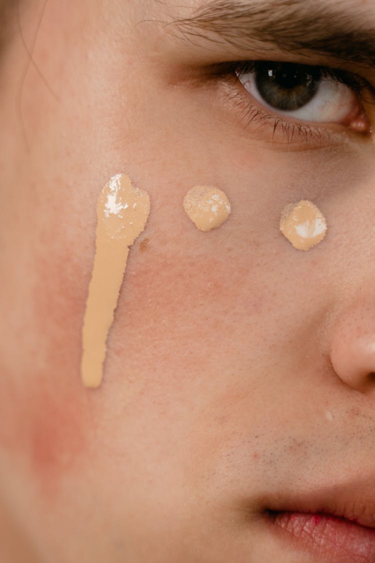 A Close-up Shot Of A Man With Concealer On His Cheek