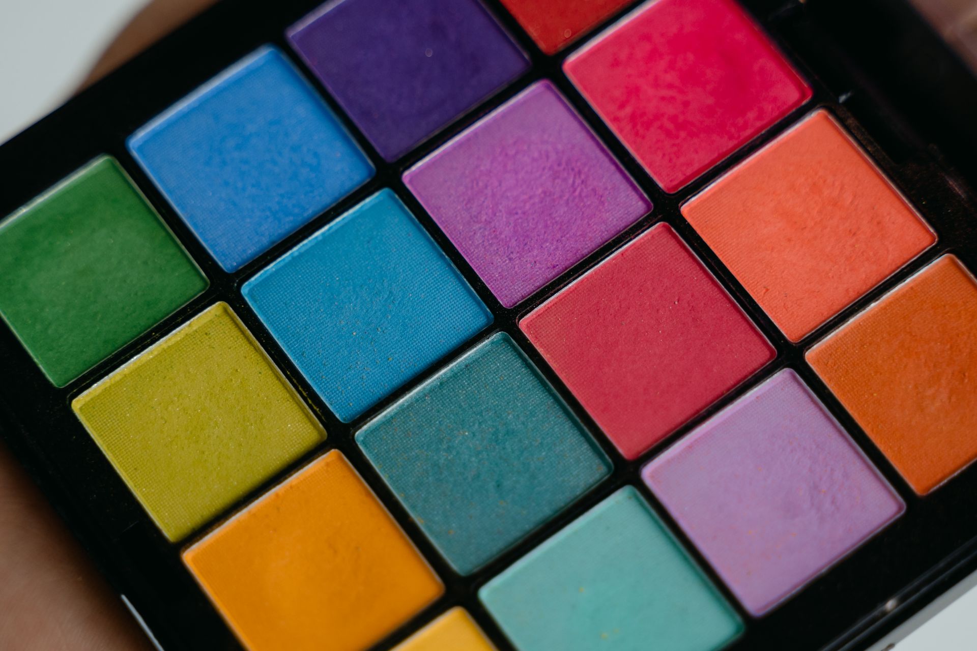 Close-up of a colorful eyeshadow palette featuring a variety of vibrant shades.