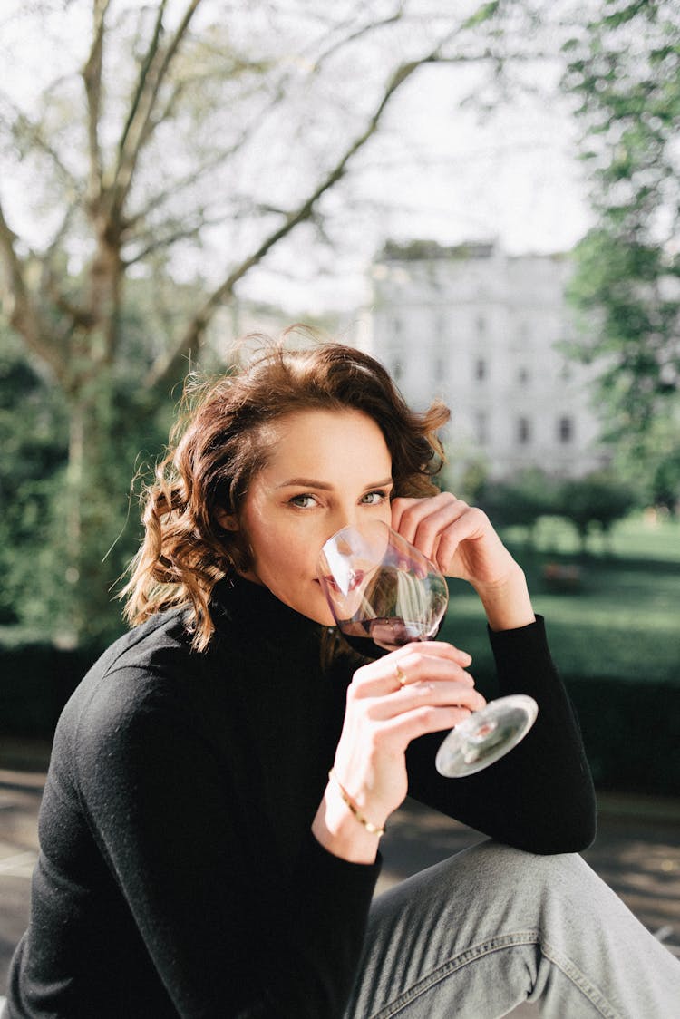 Woman Drinking Red Wine Against Urban Park