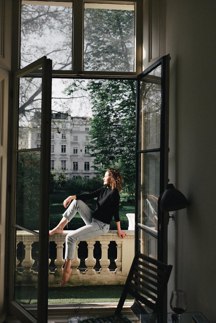 Smiling Barefoot Woman Contemplating Park From Balcony Fence