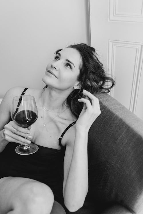 Dreamy woman with glass of wine in armchair