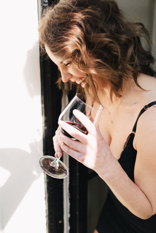 Free Cheerful woman in sleepwear with red wine at home Stock Photo