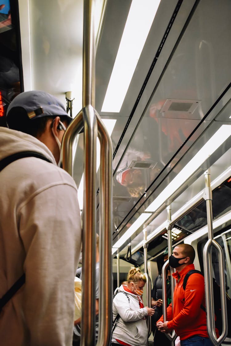 A Low Angle Shot Of People Standing Inside The Train While Wearing Face Mask