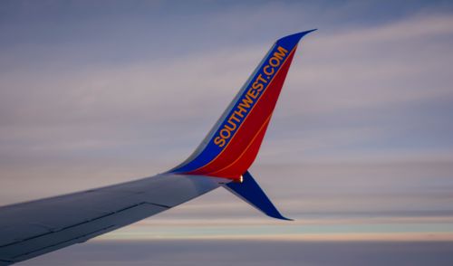 Free View of an airplane wing with a colorful winglet against a serene sky. Stock Photo