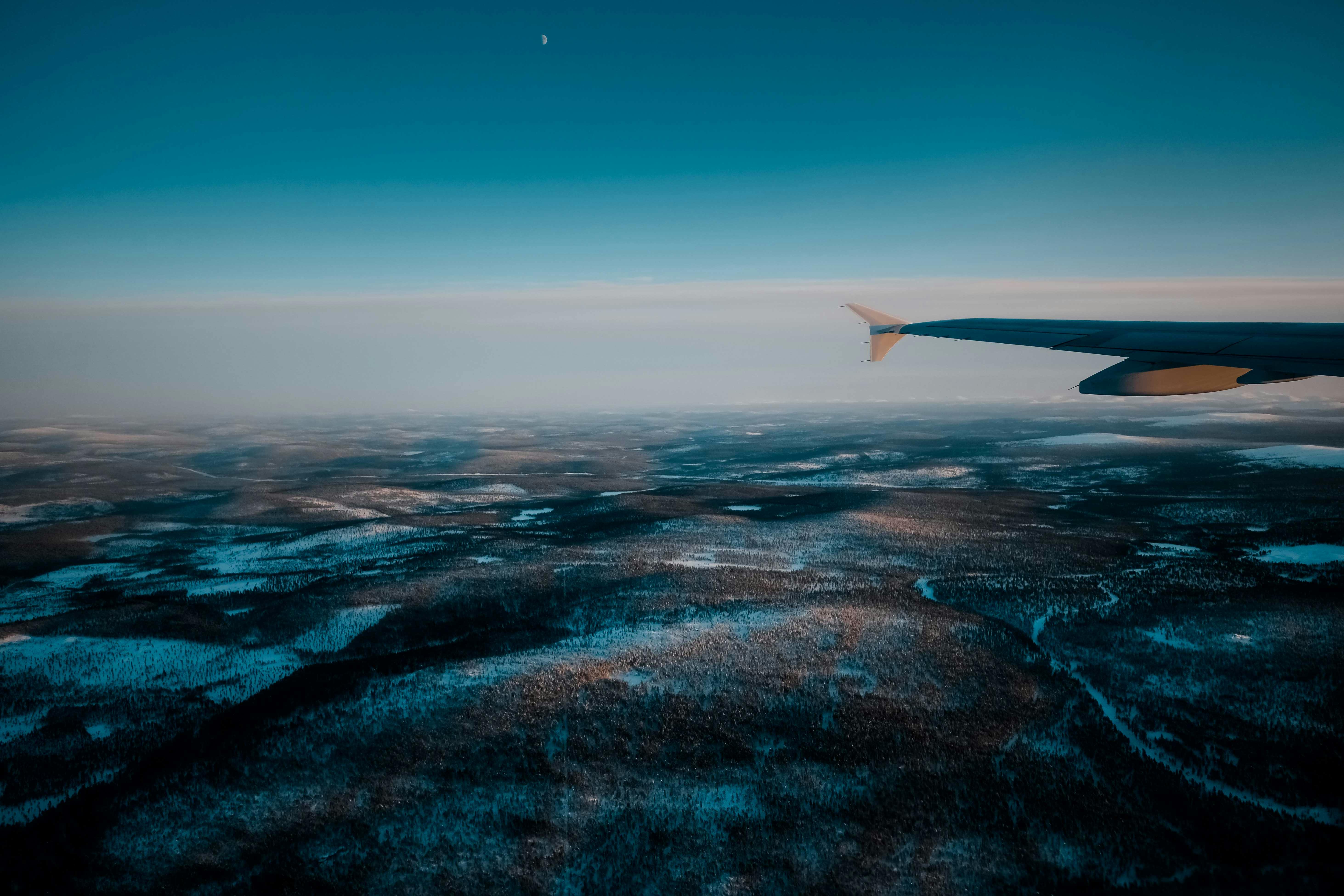 aircraft flying over wild snowy terrain at sundown