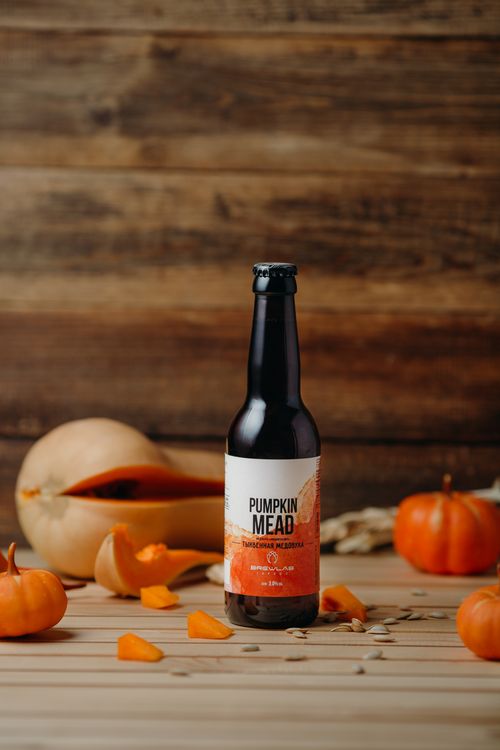 Free Bottle of pumpkin mead surrounded by autumn decorations and pumpkins. Stock Photo