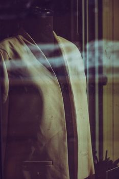 Stylish vintage beige coat on a mannequin in a store window display.
