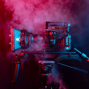 Cinema camera rig lit in coloured haze, by Ben Collins on Pexels