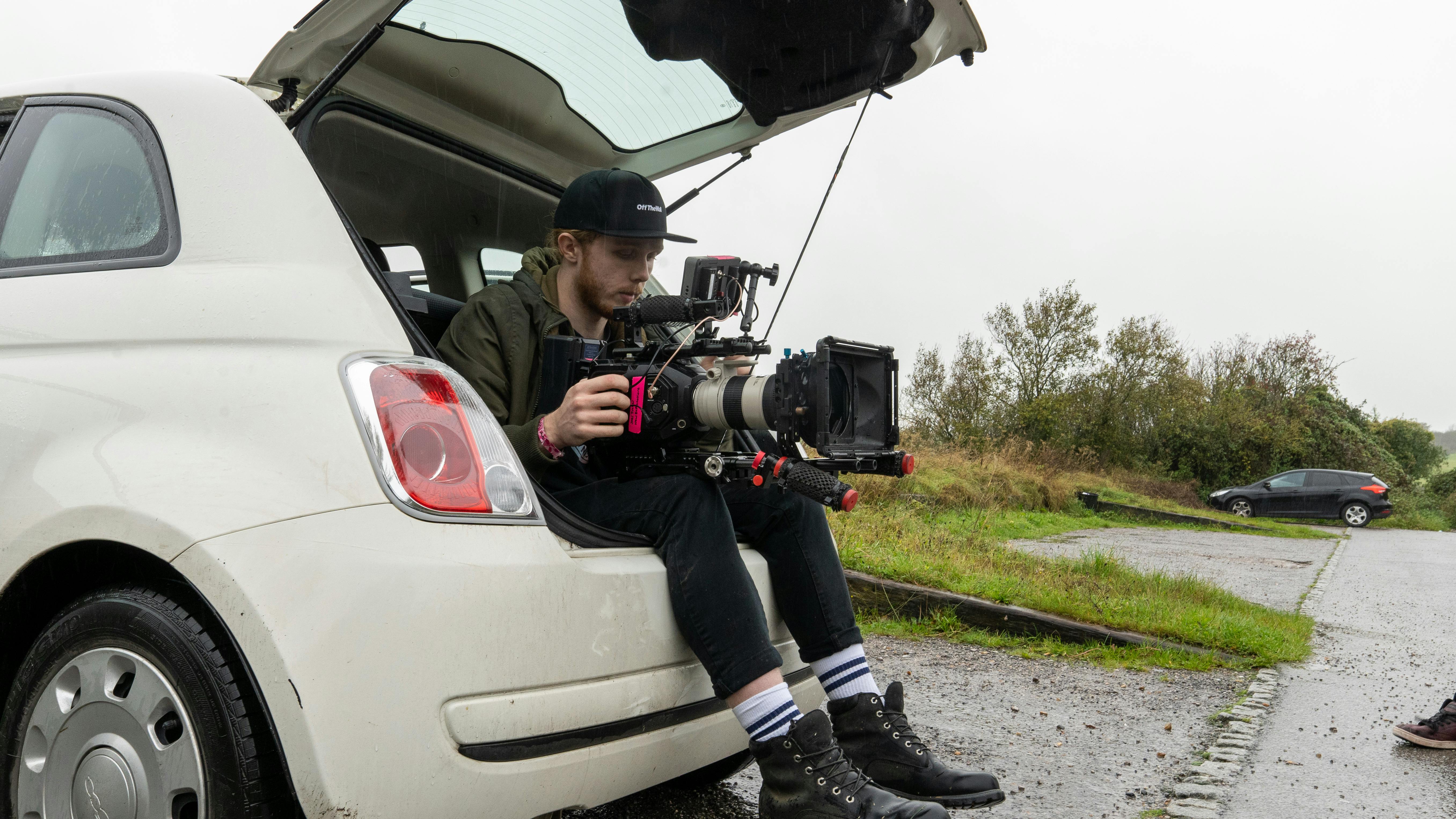 a man holding a camera while sitting at the back of the car