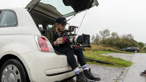 A Man Holding a Camera while Sitting at the Back of the Car