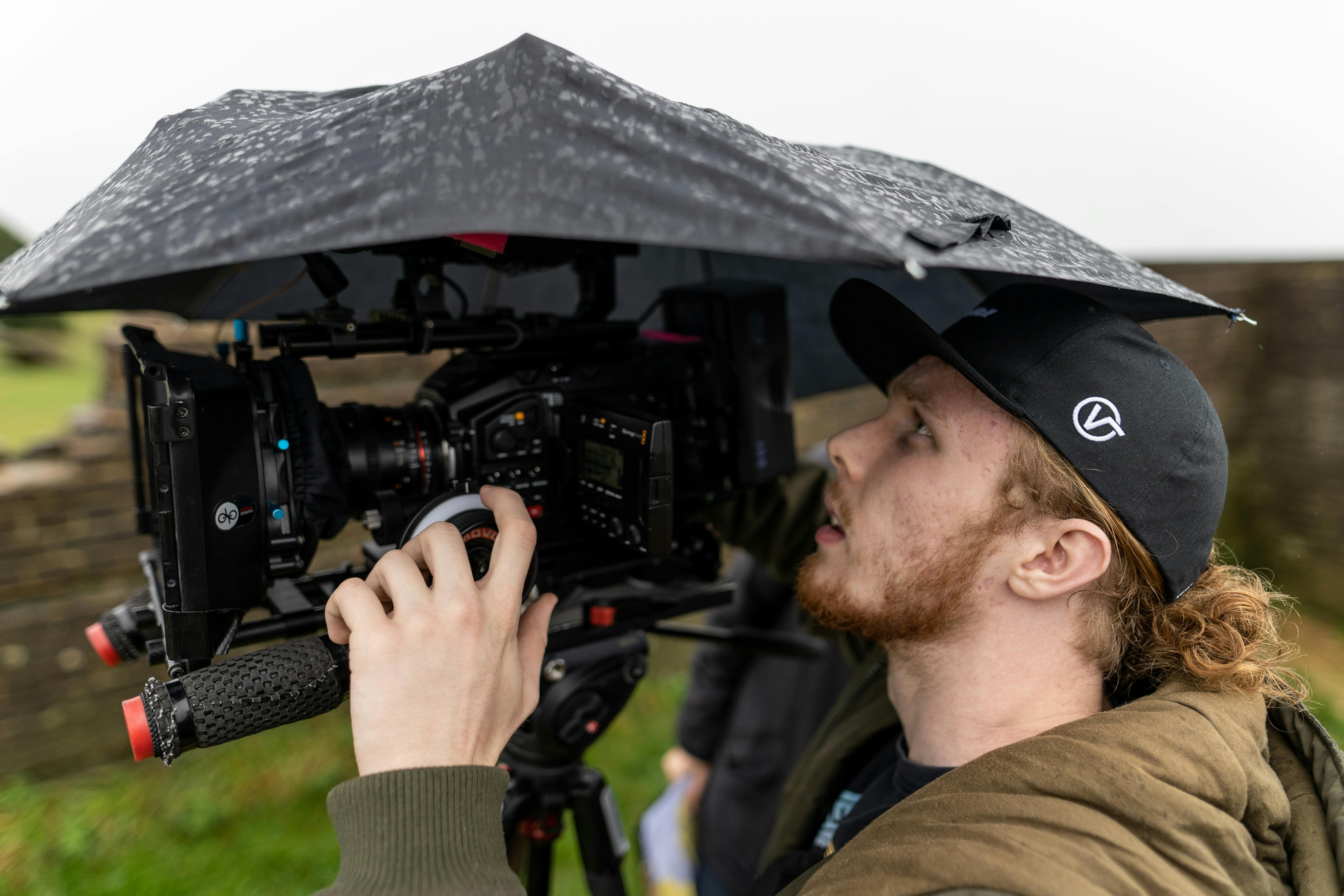 a side view of a man filming outside while raining