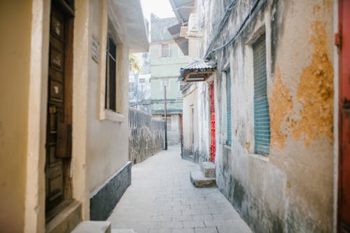 Paved narrow street between aged stone residential houses with shabby facade in city