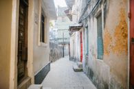 Paved narrow street between aged stone residential houses with shabby facade in city