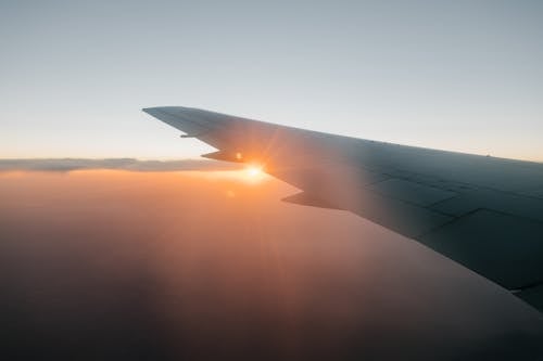 Wing of airplane flying against sunset