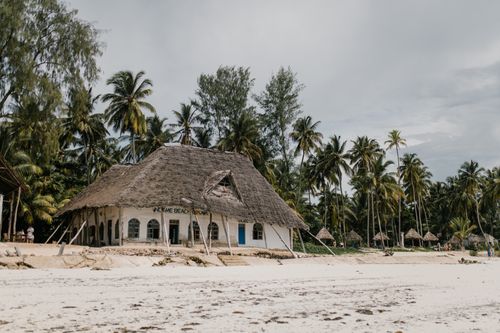 Free Bungalow with straw roof located on sandy beach with palm trees in summer Stock Photo