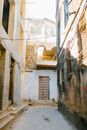 Dirty narrow street with weathered abandoned buildings on sunny day in old city