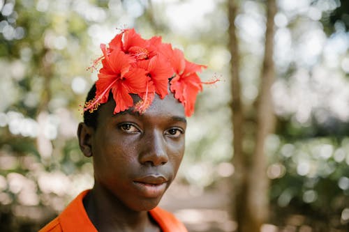 Ethnic man with flowers on head in forest