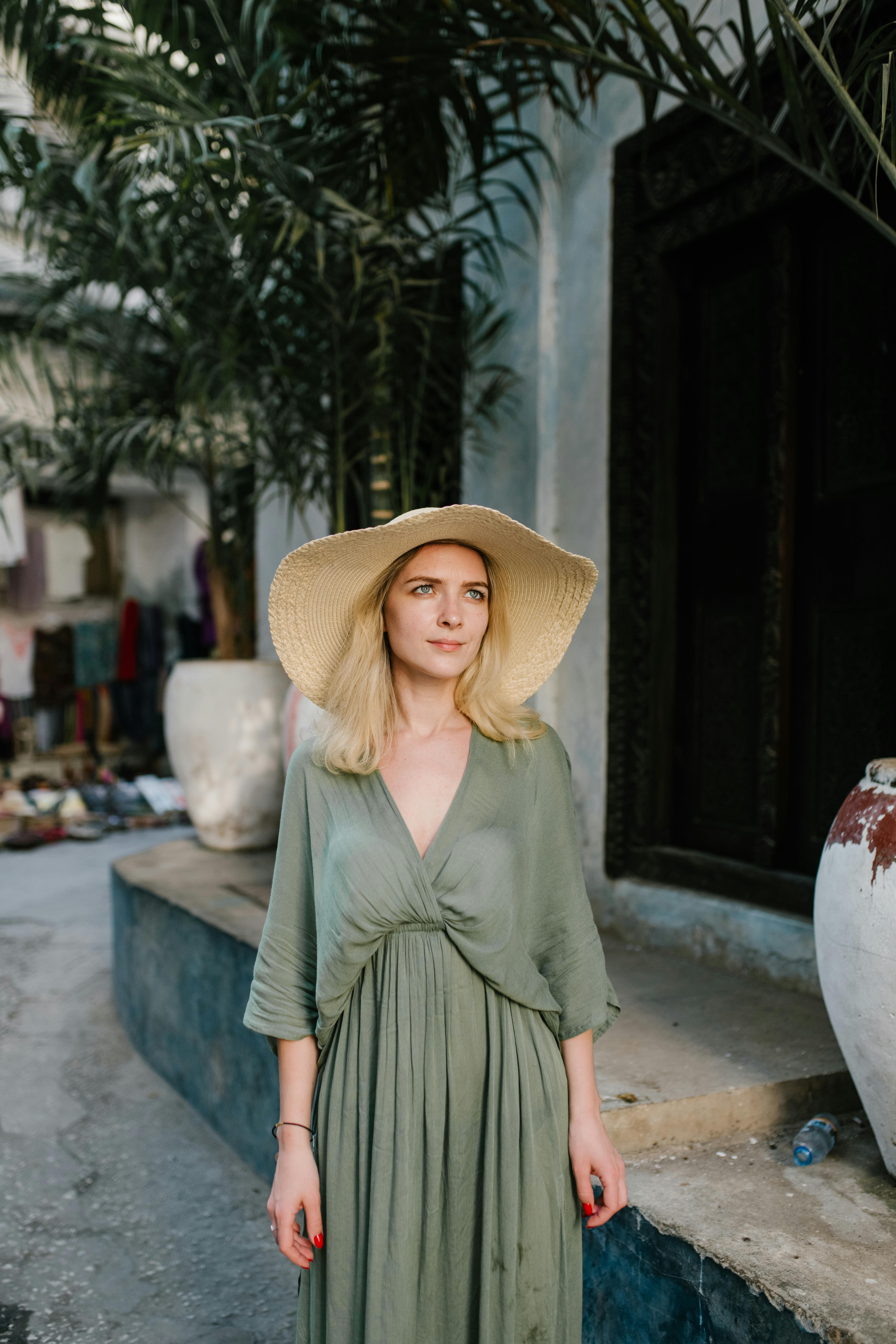 serene woman in straw hat standing near concrete building