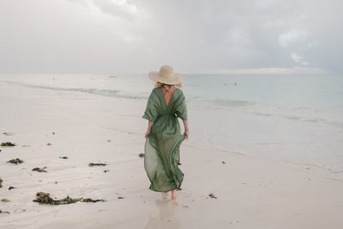 Woman walking along wet sandy beach in windy day