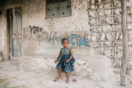 Little black girl sitting on rough stone border in ghetto