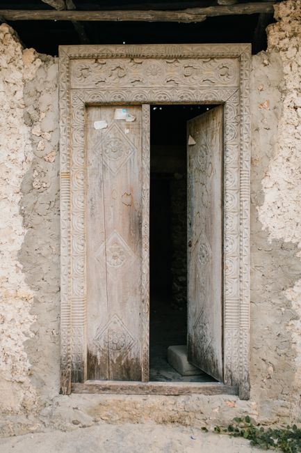 Crumbling deserted stone building with opened door at entrance located in neglected poor district