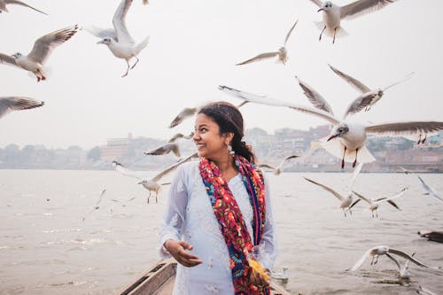 Happy Indian woman on boat against seagulls
