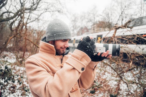 Man in Brown Coat Holding Camera