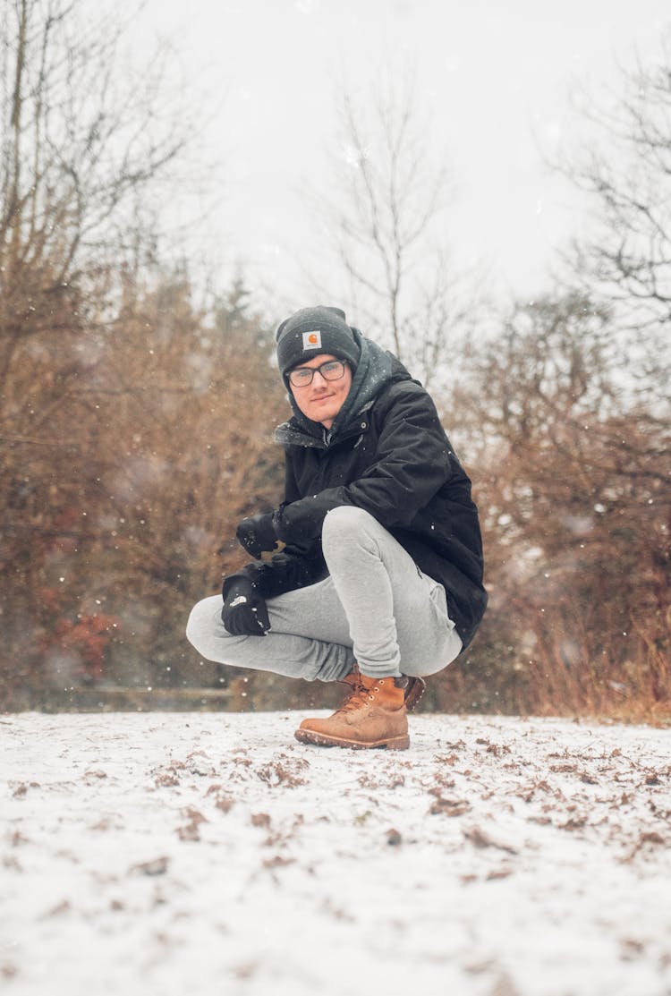 Man In Black Jacket Sitting On Snow Covered Ground