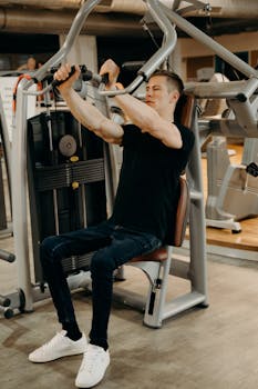 A young man works out on a gym machine, focusing on strength training.