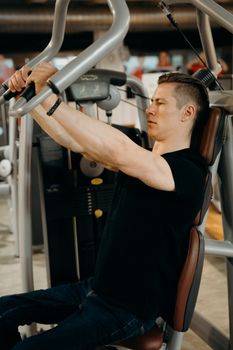 Adult man working out on a gym machine with focused expression.