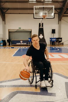 A determined wheelchair basketball player dribbling on an indoor court, showcasing athleticism and motivation.