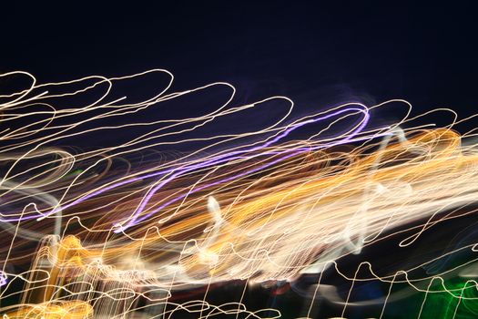 Dynamic long exposure capturing colorful light trails against a night sky.