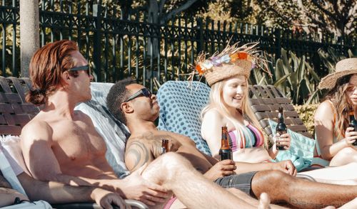 Free Group of diverse friends having fun and relaxing by the pool with drinks. Stock Photo
