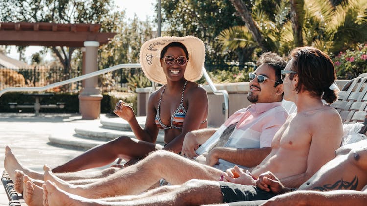 People Relaxing On The Sun Loungers